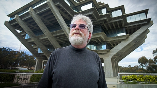 Russel Impagliazzo wearing a dark shirt and sunglasses stands outside a tree-shaped building