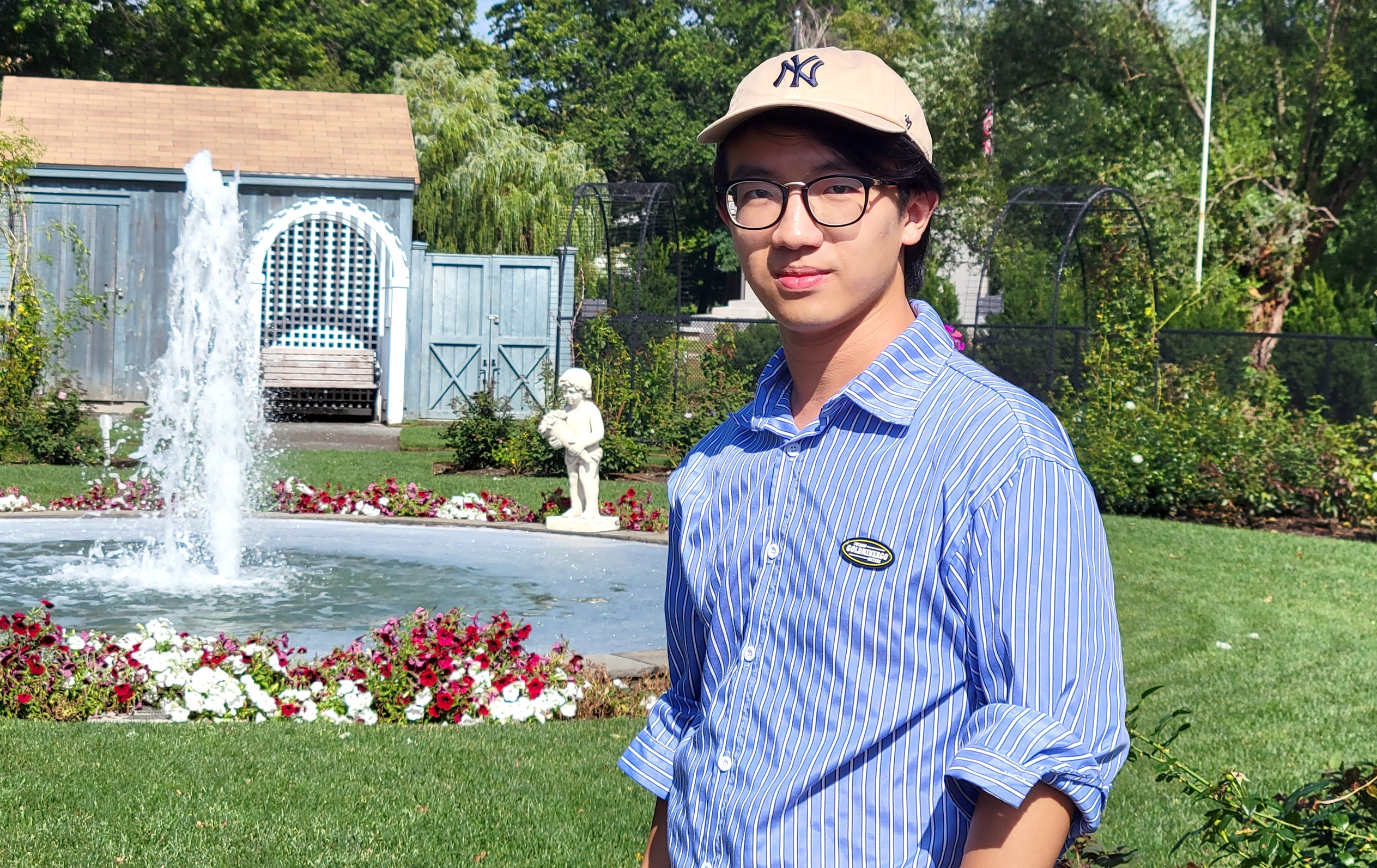 Ziming Liu in a blue shirt and Yankees cap in front of a fountain OR Ziming Liu in a burgundy sweatshirt sits at a desk working on a laptop